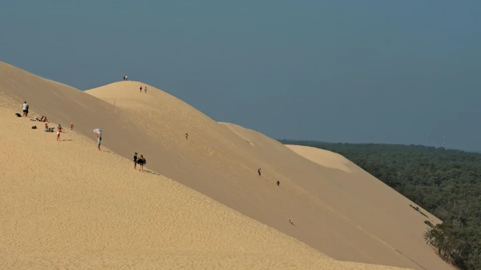 Randonneurs et familles sur les pentes de la Dune du Pilat par temps clair, proche d'Arcachon, une escapade nature idéale en train depuis Bordeaux.